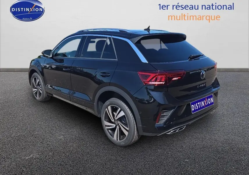Volkswagen T-Roc noir perle en 3/4 arrière droit, avec jantes alliage et barres de toit argentées visibles.
