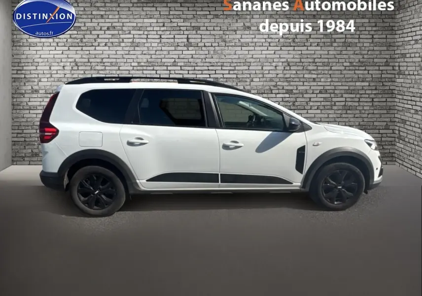 Vue latérale droite d'un Dacia Jogger blanc glacier avec jantes noires et vitres arrière surteintées.