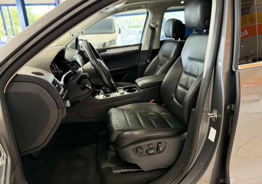 Intérieur côté conducteur du Volkswagen Touareg gris foncé 2017 avec sièges cuir noirs et console centrale visible.