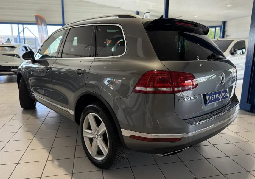 Vue 3/4 arrière droite d'un Volkswagen Touareg gris foncé en showroom, avec jantes alliage et vitres teintées.