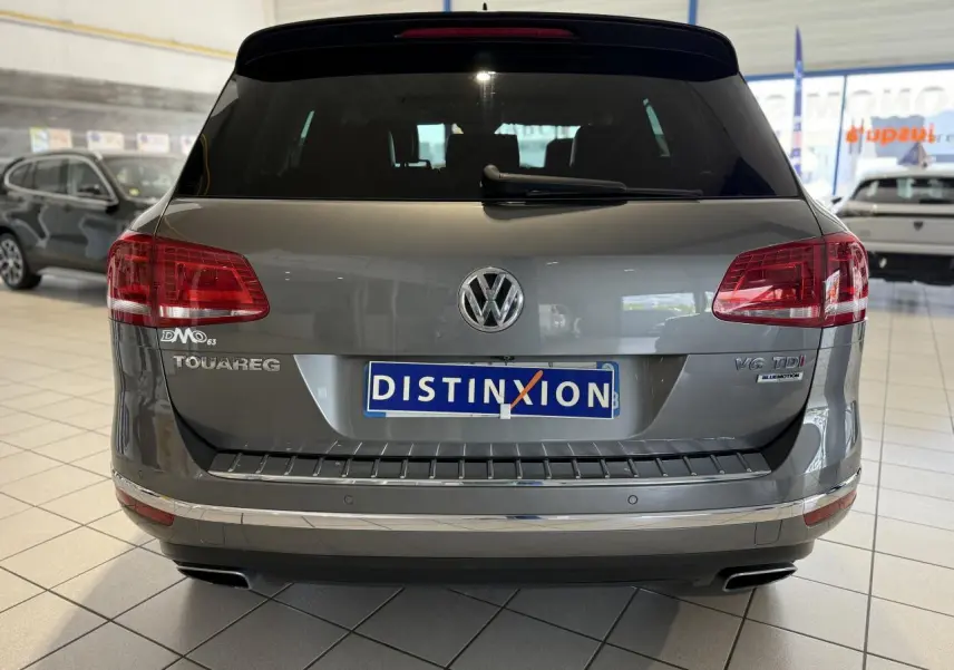 Vue arrière d'un Volkswagen Touareg gris foncé avec plaques Distinxion et badges V6 TDI BlueMotion visibles.