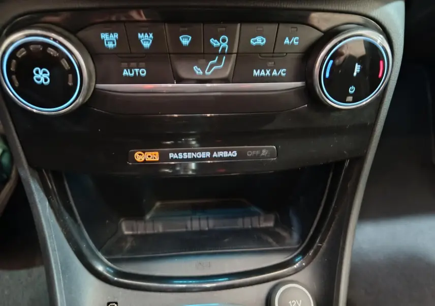 Détail du tableau de bord central noir avec commandes climatisation et témoin airbag passager du Ford Puma blanc 2022.