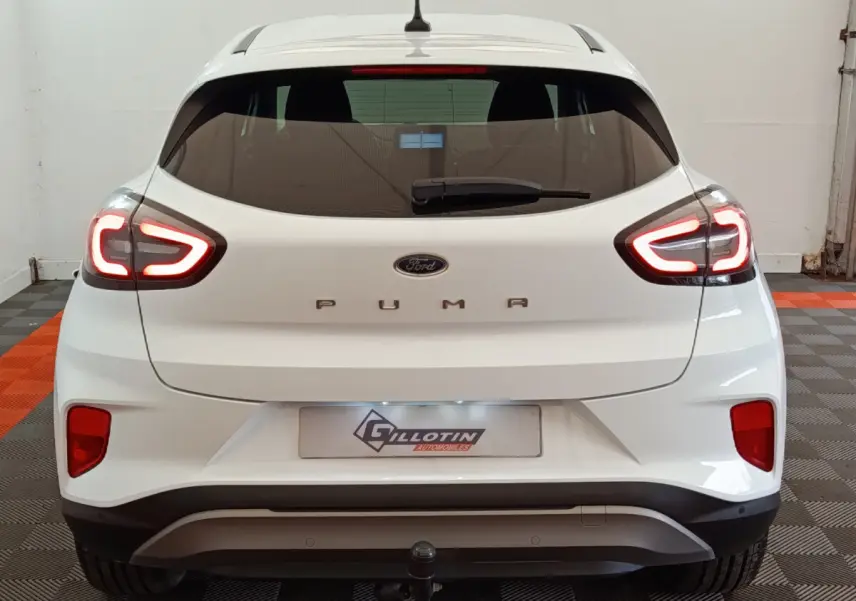 Vue arrière d'une Ford Puma blanche 2022 avec feux LED allumés et attelage visible en intérieur.