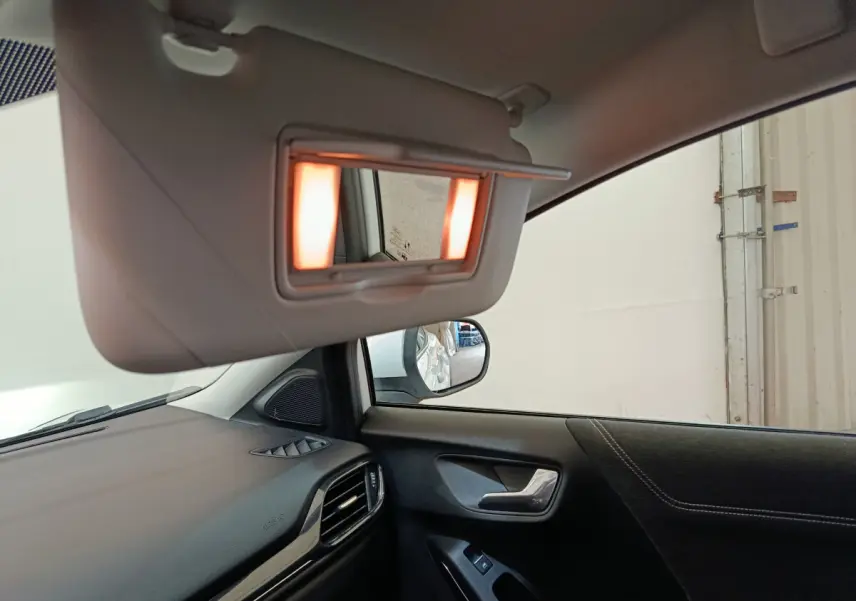 Intérieur côté conducteur du Ford Puma blanc 2022, avec miroir de soleil éclairé et tableau de bord visible.