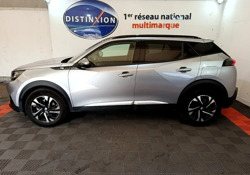 Peugeot 2008 gris clair vue de profil côté gauche, avec jantes noires et toit panoramique noir.