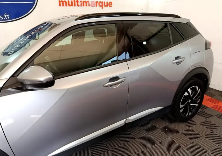 Vue latérale côté gauche d'un Peugeot 2008 gris clair avec rétroviseurs électriques et jantes noires.