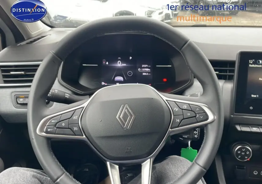 Vue intérieure centrée sur le volant multifonction noir de la Renault Clio V 2025 avec tableau de bord digital et écran tactile.