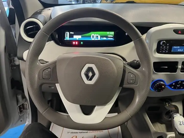 Vue intérieure centrée sur le volant gris et le tableau de bord numérique de la Renault ZOE blanc glacier électrique