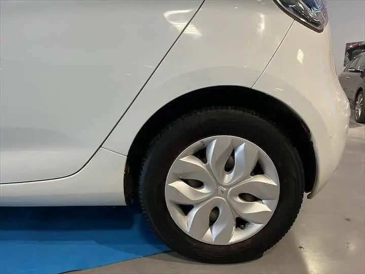 Gros plan sur la roue arrière droite blanche glacée d'une Renault ZOE R90 LIFE 41 KWh 2019 en intérieur showroom.