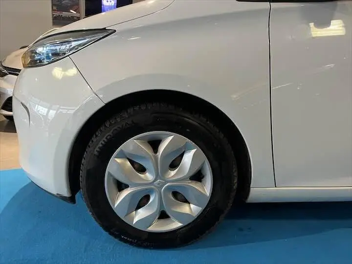 Vue latérale côté gauche d'une Renault ZOE R90 LIFE blanche Glacier, mettant en valeur l'avant et la portière.