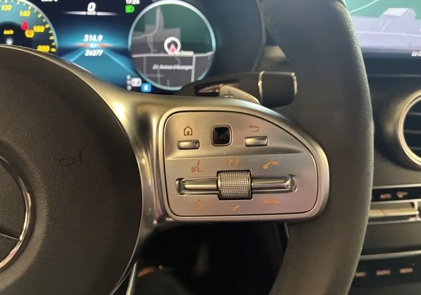 Gros plan sur la commande de volume et appels au volant cuir noir d'une Mercedes Classe C Break 220D AMG Line 2021.