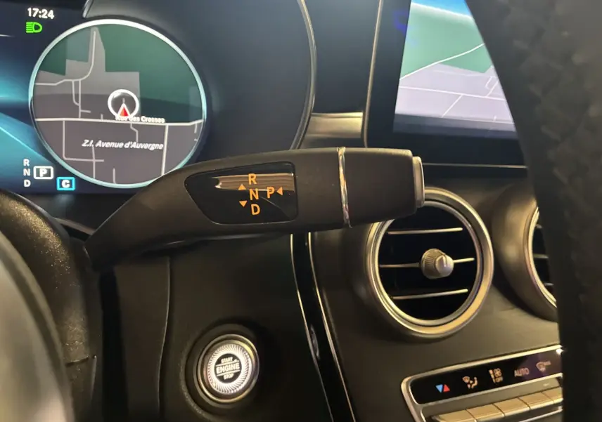 Gros plan sur la commande de boîte automatique et le tableau de bord numérique d'une Mercedes Classe C Break noir métal.