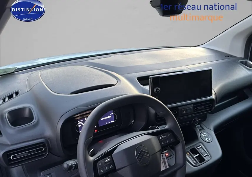 Vue intérieure du poste de conduite du Citroën Berlingo blanc 2025, volant multifonction et écran tactile central visibles.