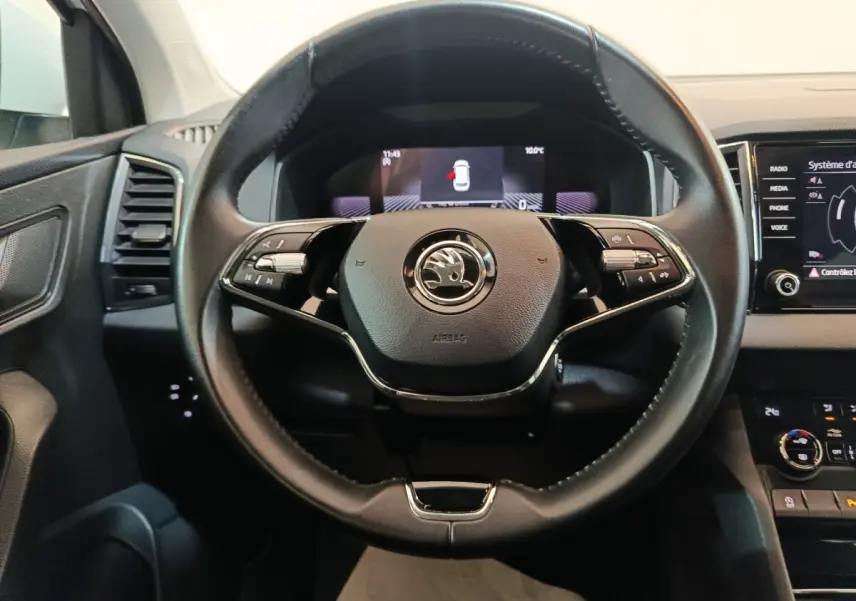 Vue rapprochée du volant cuir noir multifonctions d’un Skoda Karoq 2024 avec tableau de bord digital et écran tactile.