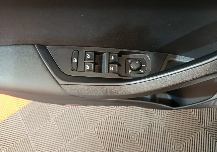 Panneau de commandes des vitres et rétroviseurs côté conducteur du Skoda Karoq blanc 2024, intérieur noir.