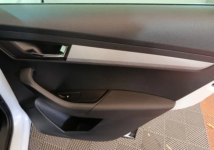 Vue rapprochée de la porte avant gauche noire avec insert décoratif gris du Skoda Karoq blanc 2024.