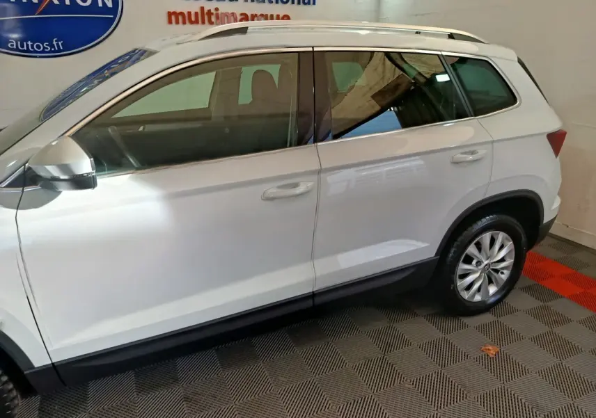 Vue de profil côté gauche d'un Skoda Karoq blanc 2024 avec jantes alliage et rétroviseurs électriques.