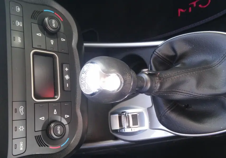 Gros plan sur la console centrale et le levier de vitesse cuir noir d'une Alfa Romeo MiTo rouge de 2010 avec boîte manuelle.