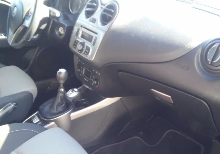 Vue intérieure côté passager de l'Alfa Romeo MiTo 2010, tableau de bord noir avec levier de vitesses manuel.