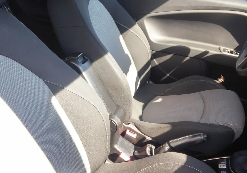 Vue intérieure côté conducteur de l'Alfa Romeo MiTo 2010 avec sièges tissu noir et gris, frein à main et volant visibles.