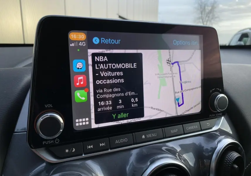 Écran tactile GPS du Nissan Juke blanc perle 2024, vue intérieure du tableau de bord avec commandes audio.