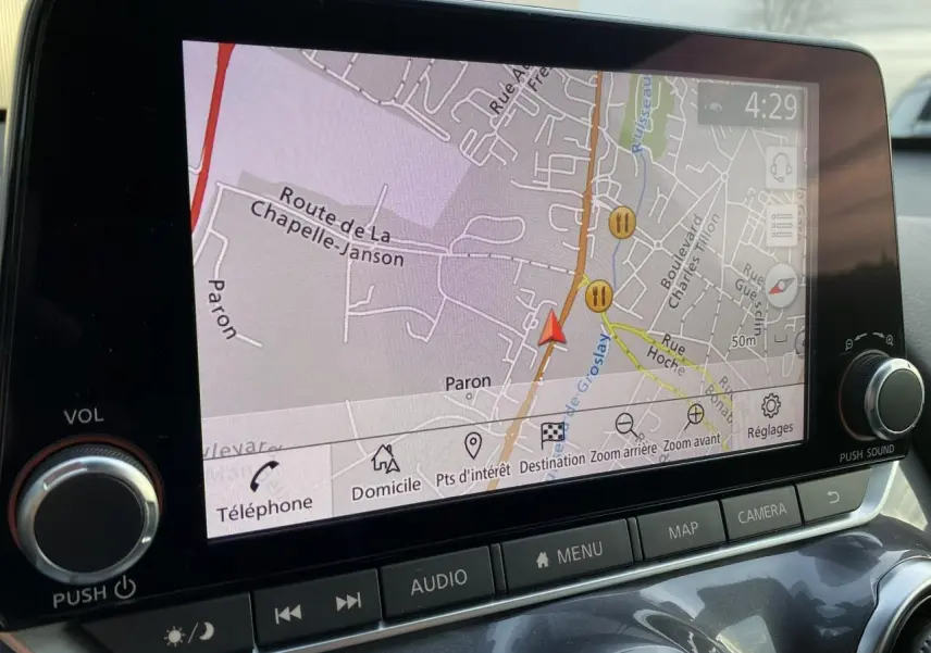 Écran tactile du système GPS du Nissan Juke blanc perle montrant une carte routière en gros plan intérieur.