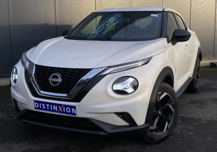 Nissan Juke blanc perle en 3/4 avant droit, avec calandre noire et jantes alliage noires distinctives.