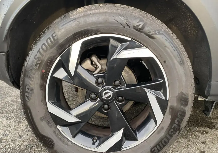 Gros plan sur la jante alliage 17'' noire et argentée du Nissan Juke blanc perle, avec pneu Bridgestone visible.