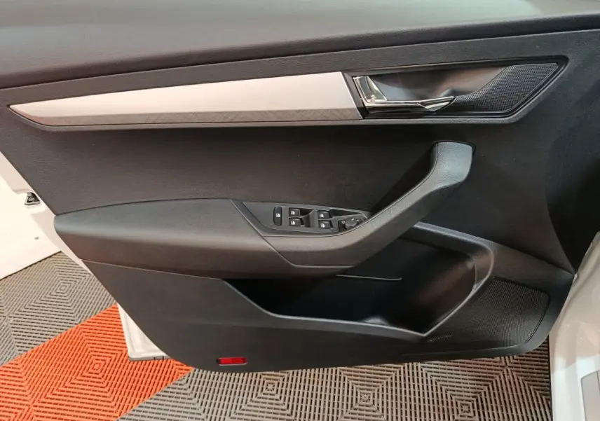 Vue intérieure côté gauche de la porte avant noire avec garniture argentée du Skoda Karoq blanc 2024.