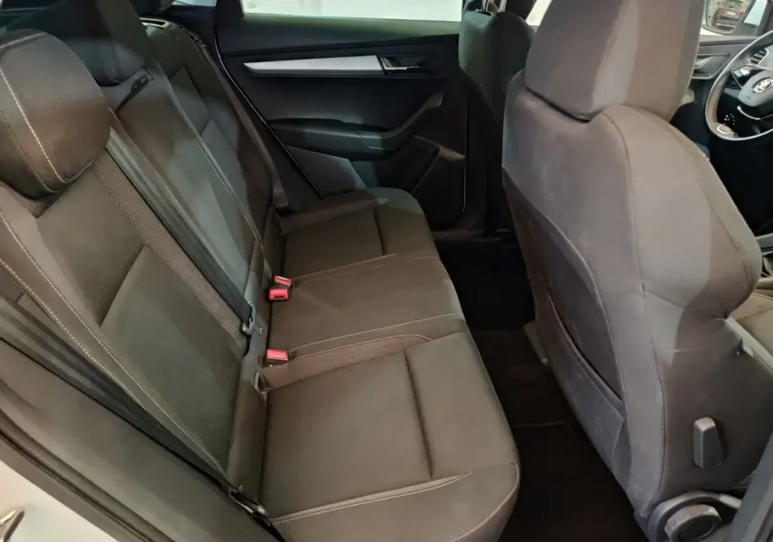 Vue intérieure côté gauche montrant la banquette arrière noire du Skoda Karoq 2024 avec sièges tissu et ceintures visibles.