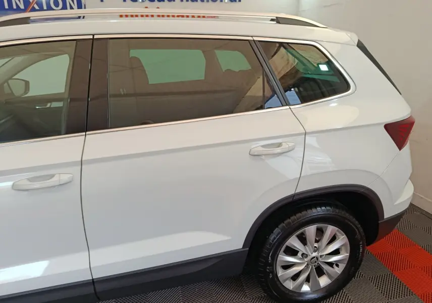 Vue latérale côté droit d'un Skoda Karoq blanc 2024 avec jante alliage et vitres teintées.