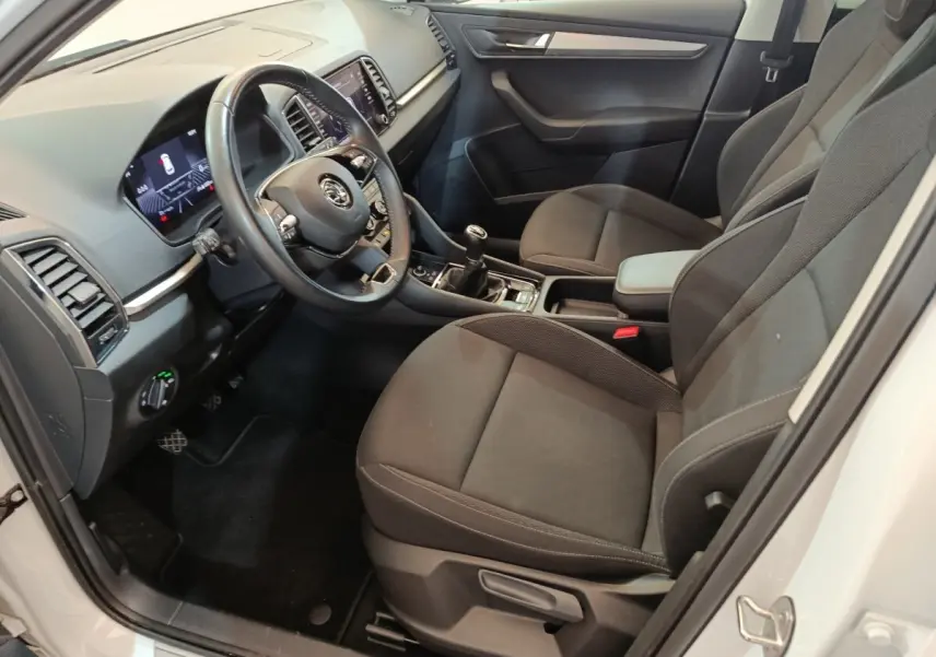 Vue intérieure côté conducteur du Skoda Karoq blanc 2024, volant cuir, tableau de bord digital et boîte manuelle.