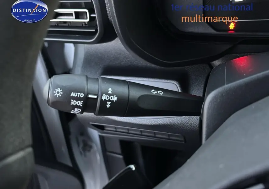 Gros plan sur la manette des feux et clignotants à gauche du volant dans l'habitacle d'un Citroën Berlingo blanc 2025.