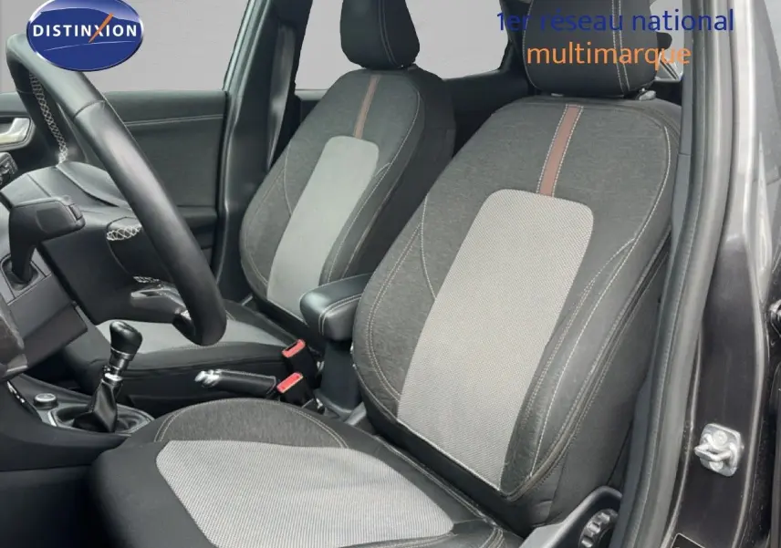 Vue intérieure côté conducteur du Ford Puma gris 2021, montrant les sièges tissu bicolore et la boîte manuelle.