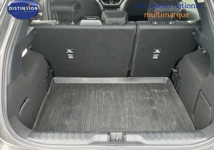 Vue arrière du coffre ouvert d'un Ford Puma gris 2021, montrant l'espace de chargement avec tapis de protection noir.