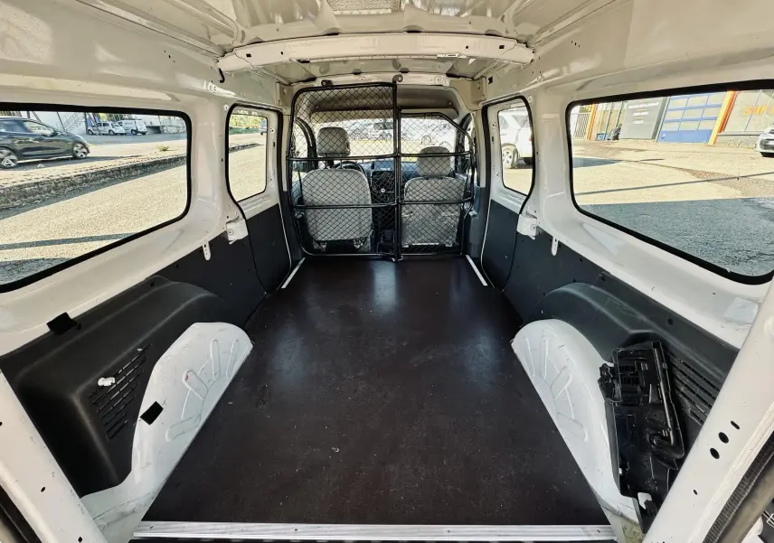 Intérieur du Renault Kangoo Maxi blanc vu de l'arrière, montrant l'espace de chargement et la grille de séparation.