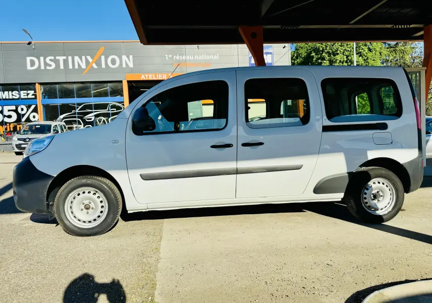 Vue de profil côté gauche d'un Renault Kangoo Maxi blanc avec jantes tôles, stationné à l'ombre.