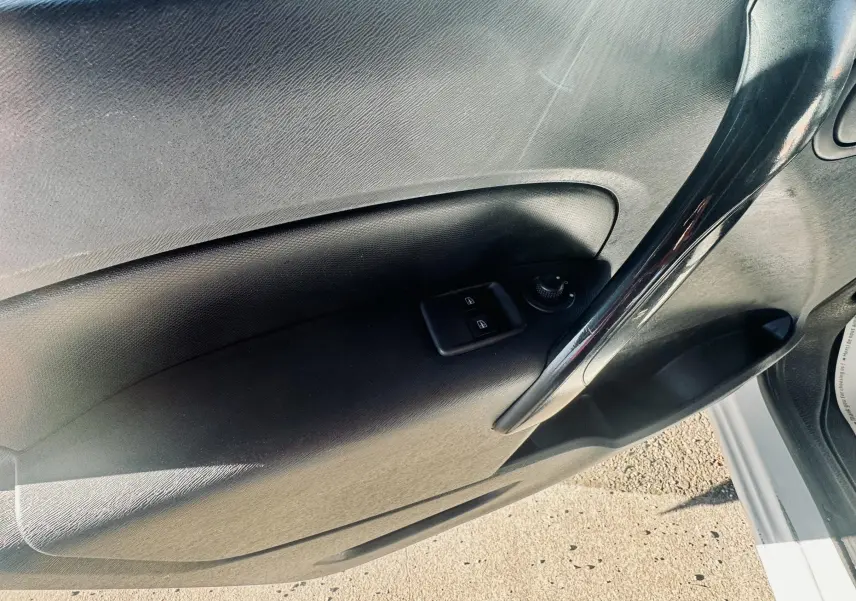 Détail de la porte intérieure côté conducteur du Renault Kangoo blanc, avec commandes électriques des vitres et poignée noire brillante.