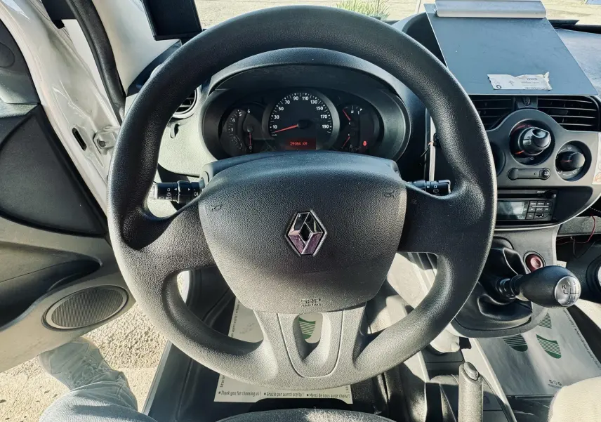 Vue intérieure centrée sur le volant noir Renault avec tableau de bord et levier de vitesse manuel visibles.