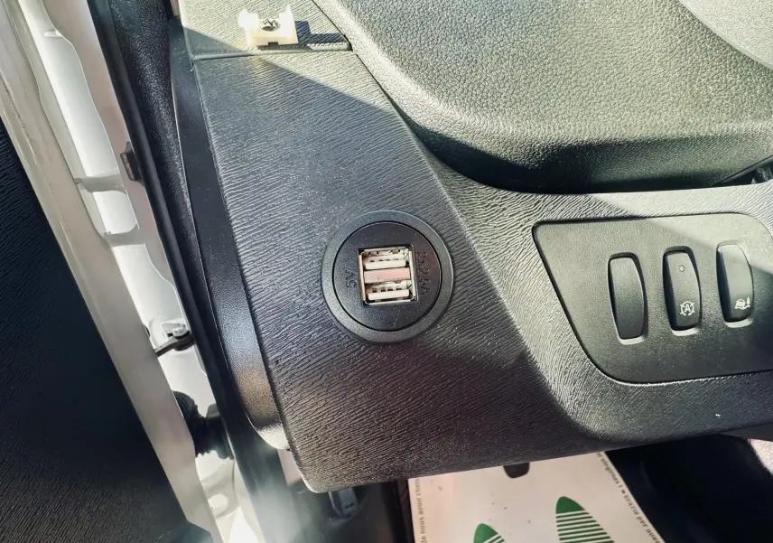 Vue rapprochée de la prise USB double et des commandes sur la console côté gauche d’un Renault Kangoo blanc.