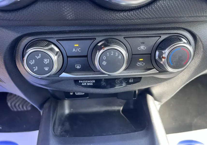 Gros plan sur les commandes de climatisation manuelle du Nissan Juke 2023, avec boutons rotatifs noirs et argentés.