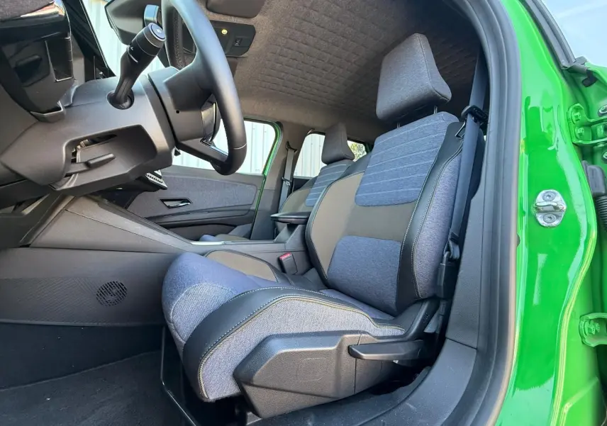 Vue intérieure côté conducteur de la Renault R5 E-Tech 2024 avec sellerie textile bleu jean et portière verte Pop ouverte.