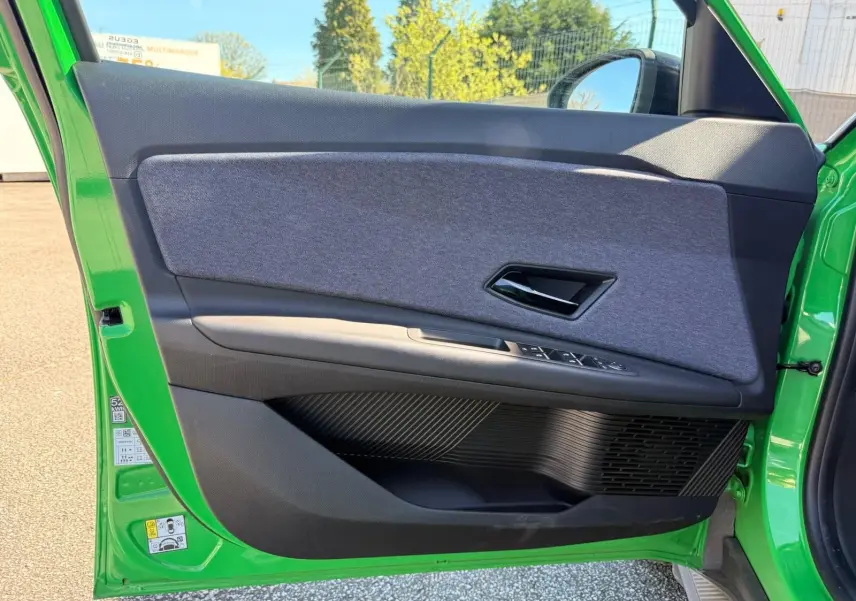 Vue côté gauche de la porte avant verte Renault R5 E-TECH avec habillage textile gris et commandes électriques.