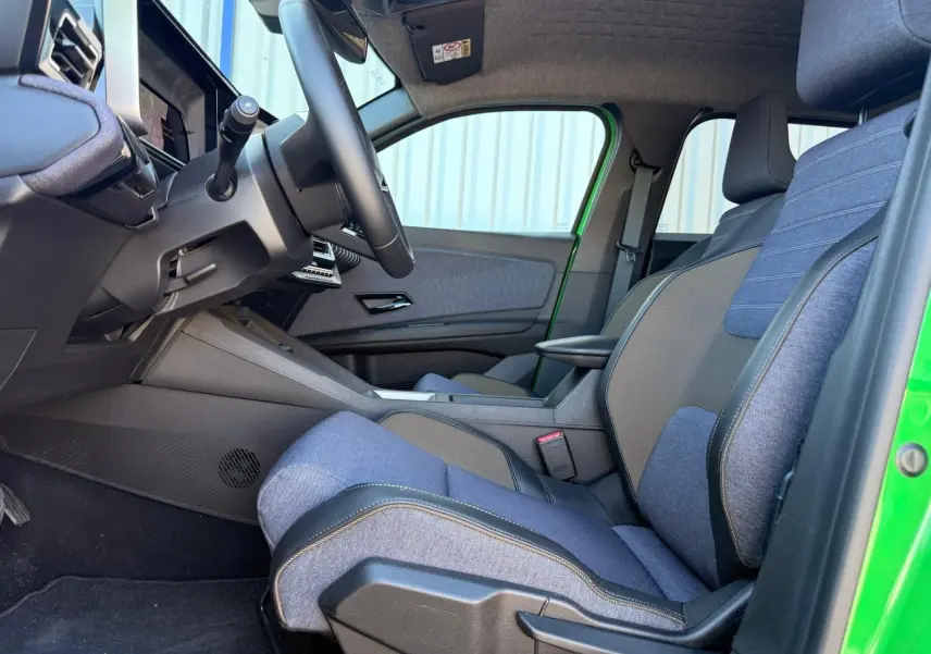 Vue intérieure côté conducteur de la Renault R5 E-TECH 100% électrique 2024, sellerie textile recyclé bleu et noir, porte verte.