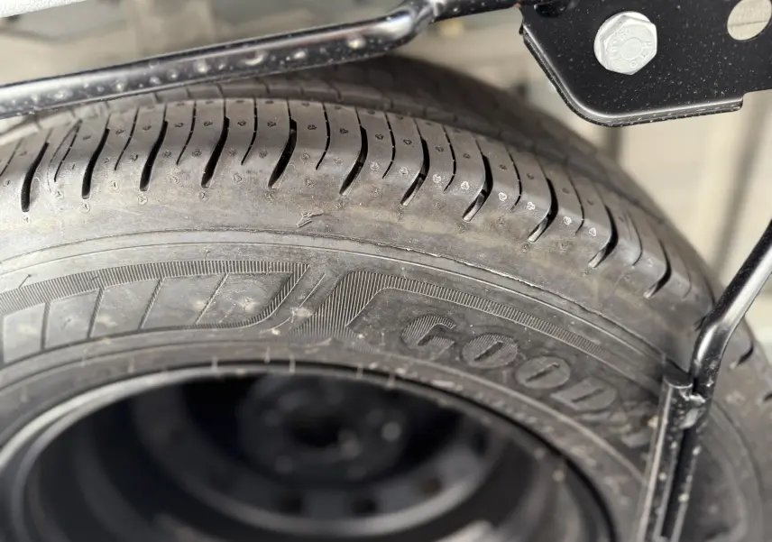 Gros plan sur le pneu de secours Goodyear sous un Renault Trafic Fourgon blanc, vue détaillée du flanc et de la fixation métallique.