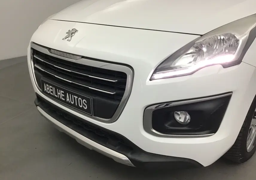 Vue de près du 3/4 avant droit du Peugeot 3008 blanc avec phares allumés et calandre noire distinctive.