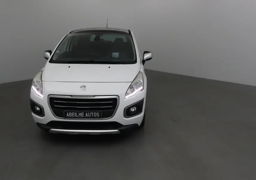 Peugeot 3008 blanc vue de face avec phares allumés dans un studio neutre.