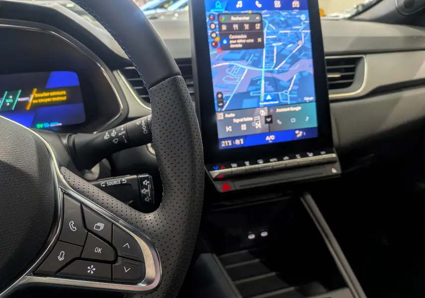 Intérieur du Renault SYMBIOZ gris Cassiopé, vue sur le volant perforé et l'écran tactile central affichant la navigation.