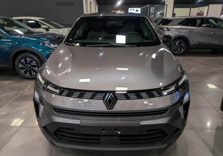 Vue frontale du Renault SYMBIOZ gris Cassiopé en showroom, mettant en valeur sa calandre moderne et ses phares LED fins.
