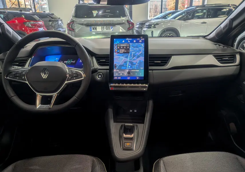 Vue intérieure centrée sur le tableau de bord et volant du Renault Symbioz gris, avec écran tactile vertical et commandes modernes.